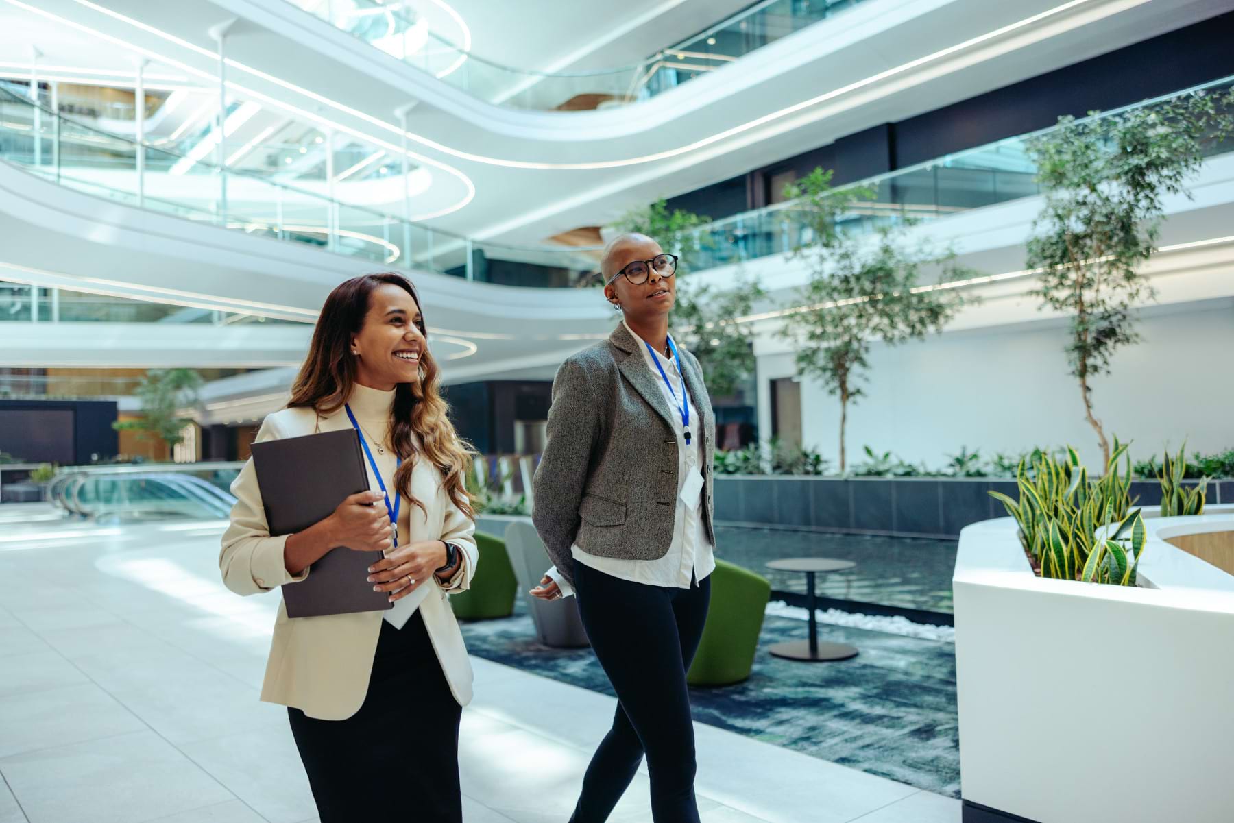 Business professionals in modern sustainable workplace Two business professionals walking through a modern eco-friendly office building, representing careers in sustainability and corporate responsibility